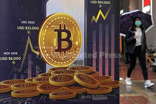 FILE - An advertisement for Bitcoin cryptocurrency is displayed on a street in Hong Kong, Thursday, Feb. 17, 2022. Markets this year are roiling, uncertainty abounds and the U.S. govement has had to step in to rescue two large American banks in recent days. So why is Bitcoin, considered among the riskiest bets of them all, rising so fast? (AP Photo/Kin Cheung, File)